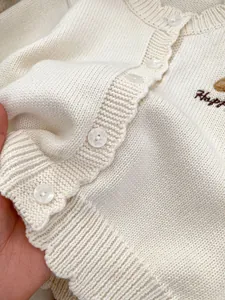 Detailopname van gebreid babyvest met schattig berenborduursel en geribbelde textuur