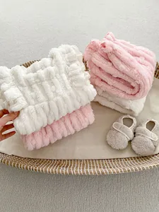 Close-up of thick waffle textured baby blankets and soft fleece shoes in a basket