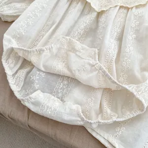 Detail shot of baby romper showing delicate lace trim and white resin snap buttons