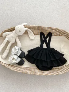 Vista piatta del set neonata con pagliaccetto a balze e peluche a forma di coniglietto