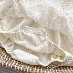 Detail of baby waffle knit romper with delicate lace snowflake trim and resin snaps