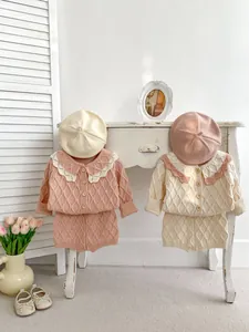Détail du tricot en nid d'abeille et des boutons en bois sur les ensembles rose et crème
