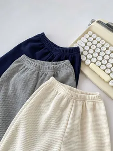 Close-up of baby waffle knit pants in navy, grey, and cream with elastic waist detail