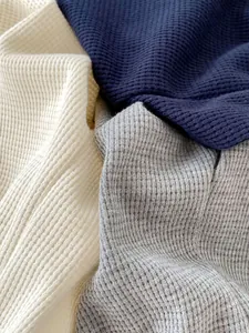 Detailed macro view of soft waffle texture fabric in cream, navy, and grey colors