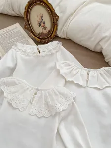 Detailed view of white baby shirt featuring intricate lace collars and button back design