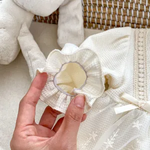 Detailed macro view of cream waffle knit baby dress with lace trim and mesh skirt