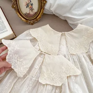 Close-up of baby dress featuring floral embroidery and large lace collar detail