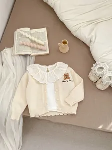Detail van babygebreid vest met delicate kantkraag en schattig teddybeerborduurwerk