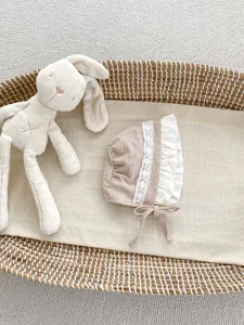 Dettaglio della cuffia per neonata con pizzo ricamato a fiori e laccio regolabile