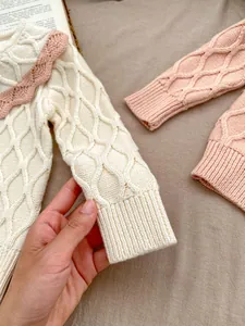 Détail de la texture en maille nid d'abeille et col en dentelle rose sur le pull bébé