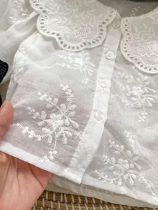 Dettaglio della camicia bianca per neonata con ricami floreali e colletto a Peter Pan raffinato