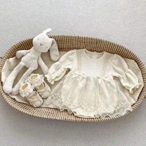 Detail of cream waffle knit baby romper with lace mesh skirt and satin bow accents