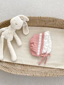 Dettaglio della cuffia rosa neonato in cotone con pizzo bianco e ricamo elegante