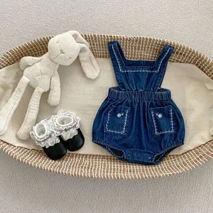 Détails d'une combinaison bébé en denim brodé avec motifs fleurs en panier