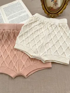 Détail de shorts en maille pour bébé en crème et rouge brique avec texture nid d'abeille