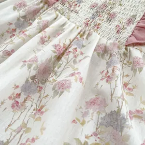 Dettaglio di pagliaccetto floreale neonata con ricamo a punto smock rosa e volant