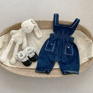 Détail d'une barboteuse en jean pour bébé avec broderies florales et taille élastique
