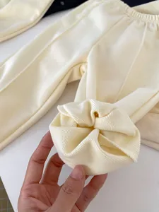 Close-up of beige knitted baby bodysuit fabric showing soft texture and ribbed cuffs