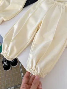 Detail of soft cream knitted baby onesie showing elastic cuffs and premium cotton texture