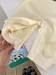 Detail of snap button closures on the crotch of a cream-colored baby romper