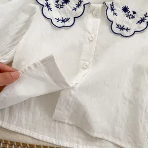 Vue détaillée d'une chemise blanche avec grand col festonné orné de broderies florales bleues