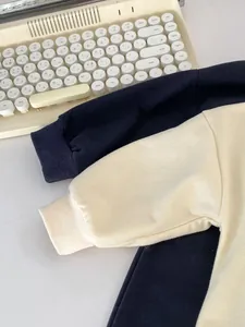Close-up of ribbed cuffs on embroidered baby rompers in navy and cream white colors