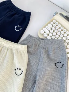 Detailed macro view of waffle knit fabric texture and smiley embroidery on boy's trousers