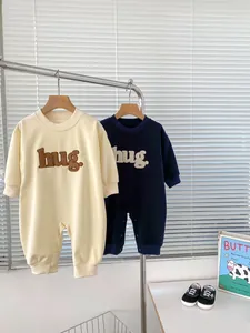 Detail of infant long sleeve rompers featuring hug embroidery and snap button closure