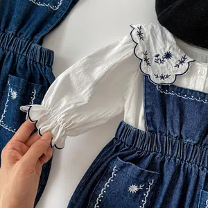 Détail du col fleuri brodé sur la chemise en coton et la robe chasuble en jean