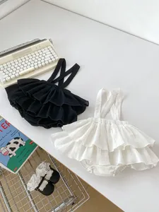 Detail of ruffled baby suspender bloomers in black and white breathable cotton fabric