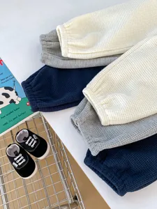 Texture detail of toddler waffle knit joggers in cream, grey, and navy colors