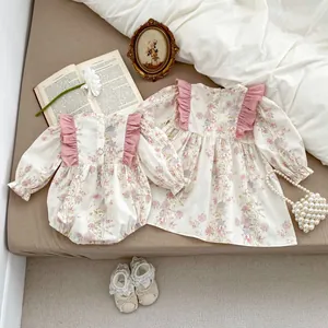 Dettaglio di pagliaccetto e abito floreale per neonati con balze rosa e bottoni sul retro