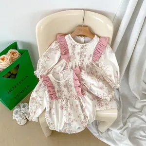 Dettaglio di pagliaccetto e abito floreale per neonata con volant rosa e pieghe sul petto