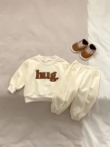 Detail of baby autumn set featuring soft fabric texture and hug letter embroidery