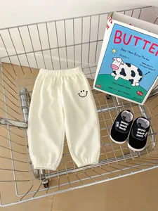 Close-up of off-white waffle knit toddler pants with smiley face embroidery in a cart