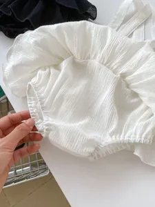 Detail of white cotton ruffled romper with elastic texture and soft ruffled hem design