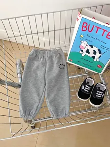 Close-up of grey waffle knit toddler joggers with embroidered smiley face detail