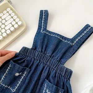 Détail de la barboteuse en jean pour bébé avec taille élastique et broderie de fleurs