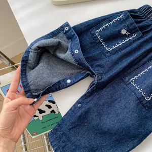 Détail de barboteuse en jean bébé avec boutons pression et broderie de tournesol