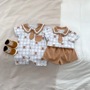 Flat lay of baby rompers with brown bear print and navy collars on soft fabric