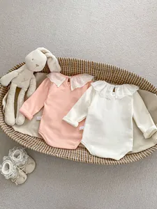 Close-up of baby bodysuits featuring delicate lace collars and soft cotton texture