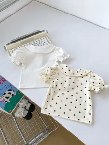 Detail view of two baby girls' Peter Pan collar short sleeve tops in white and polka dot
