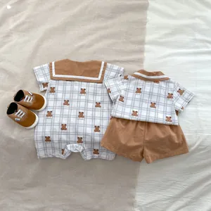 Detailed view of baby cotton rompers with brown bear print and white checkered fabric