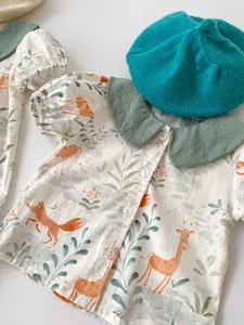 Detail of short-sleeved baby shirt featuring a green Peter Pan collar and animal prints