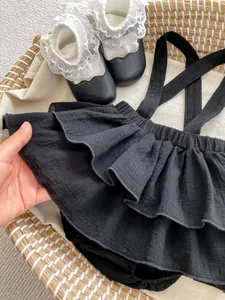 Detailed texture of black ruffled baby bloomers with lace socks in a woven basket