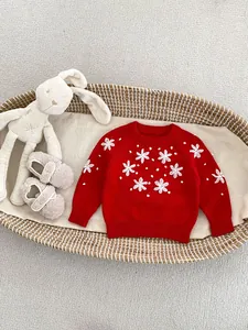 Red knit baby romper with white floral embroidery and 3D pompoms in a woven basket