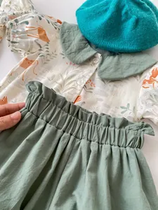 Detail of baby summer set showing giraffe print shirt and sage green elastic pants