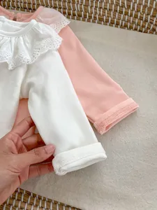 Close-up of delicate lace ruffle collar on soft cotton long sleeve baby bodysuit