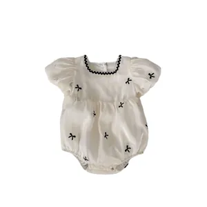 Crème baby romper met zwarte strikborduring, pofmouwen en golvende kanten details