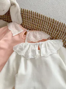 Detail of baby bodysuits with lace Peter Pan collars in pink and cream cotton fabric